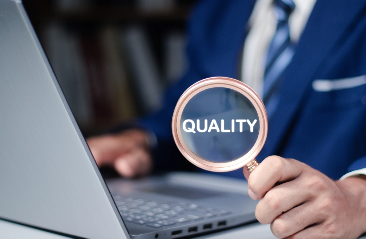 Magnifying glass highlighting "quality" near laptop